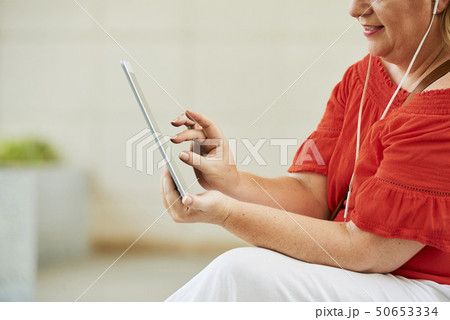 Woman zooming in video on tablet Woman zooming in video on tablet 50653334