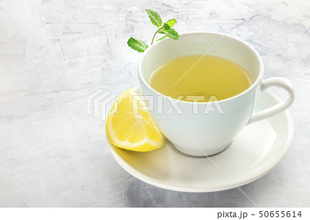 A cup of green tea with a wedge of lemon and mint leaves, with a place for text 50655614