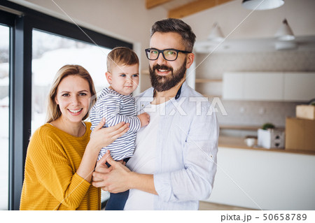 A portrait of young family with a toddler girl moving in new home. 50658789