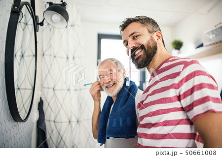 An adult hipster son and senior father in bathroom indoors at home, having fun. An adult hipster son and senior father in bathroom indoors at home, having fun. 50661008