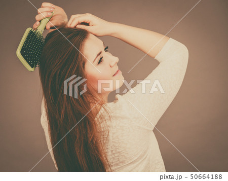 Happy woman brushing her hair Happy woman brushing her hair 50664188