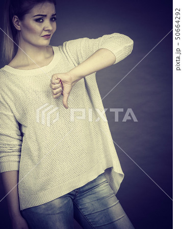 Sad woman showing thumb down gesture Sad woman showing thumb down gesture 50664292