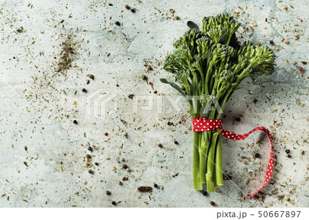 bunch of broccolini on a stone surface 50667897