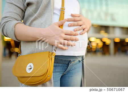 Pregnant woman is walking in the city  50671067