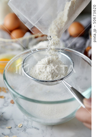baker hands sifting flour in bowl. baker hands sifting flour in bowl. 50673620