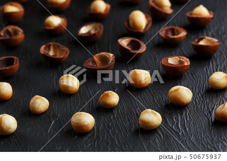 Purified and shell repeats macadamia nuts on black textural stone background. Healthy eating concept Purified and shell repeats macadamia nuts on black textural stone background. Healthy eating concept 50675937