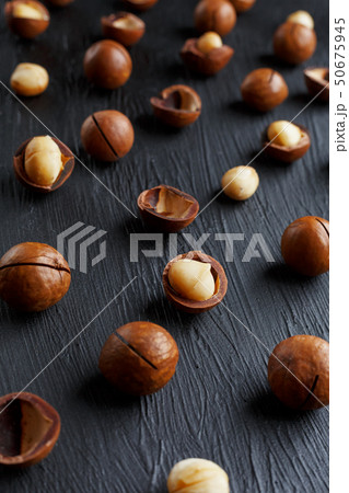 Purified and shell repeats macadamia nuts on black textural stone background. Healthy eating concept 50675945