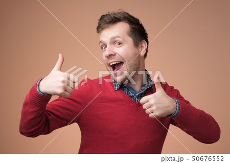 Happy handsome man in red sweater showing thumbs up 50676552