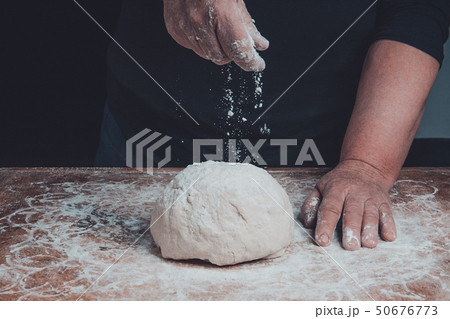 The hands of an old grandmother sprinkle with 50676773