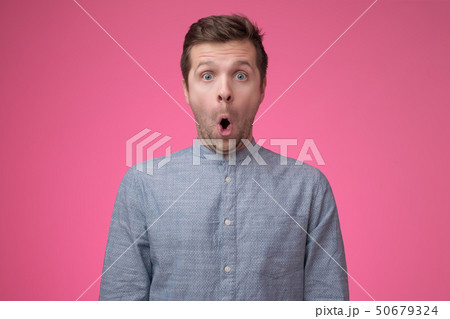 Shocked face of caucasian man in blue shirt on pink background Shocked face of caucasian man in blue shirt on pink background 50679324