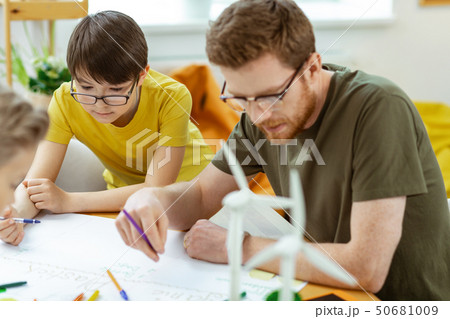 Concentrated teacher in clear glasses carrying colorful pencils 50681009