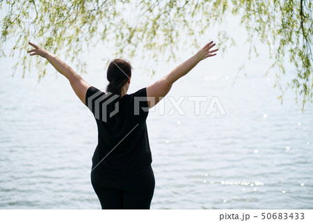 Overweight woman rising hands, view from the back Overweight woman rising hands, view from the back 50683433