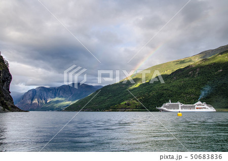 Sailing ship on a Norway fjord with mountains behind and rainbow and clouds above Sailing ship on a Norway fjord with mountains behind and rainbow and clouds above 50683836