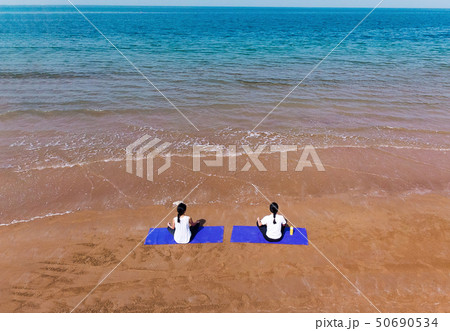 Woman meditating on the beach aerial Woman meditating on the beach aerial 50690534