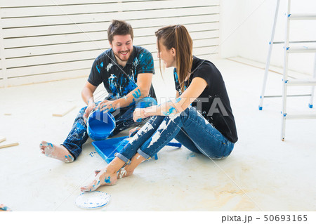 People, renovation and repair concept - portrait of happy couple pour paint People, renovation and repair concept - portrait of happy couple pour paint 50693165