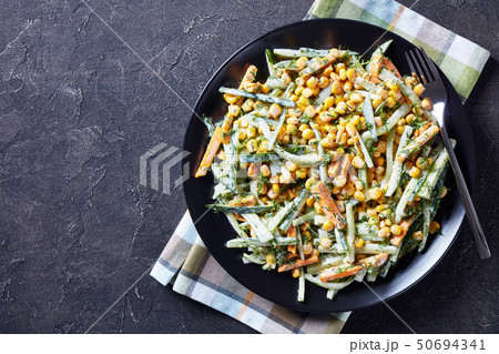 cucumber corn cheese salad on a black plate 50694341