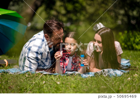 Family Lying On The Blanket In The Park. Daughter Holding Soap Bubbles. Family Lying On The Blanket In The Park. Daughter Holding Soap Bubbles. 50695469