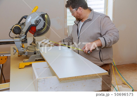 Workers installing laminate and measuring Workers installing laminate and measuring 50696575