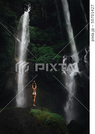 Beautiful young woman in bikini relaxing in front of waterfall. Ecotourism concept image travel girl 50701427