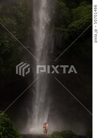 Young couple enjoying the freshness of nature under a waterfall in the tropics. The young pair Young couple enjoying the freshness of nature under a waterfall in the tropics. The young pair 50701466