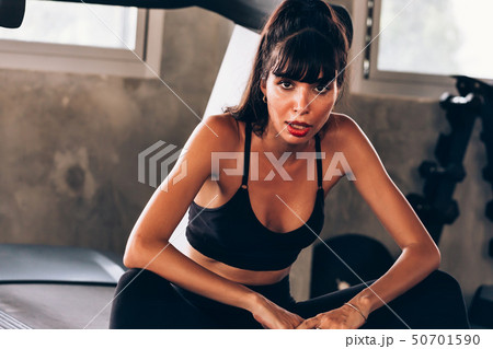 Young sweaty woman sitting on treadmill in gym 50701590