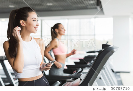 Training with music. Girl doing cardio exercise on treadmill 50707710