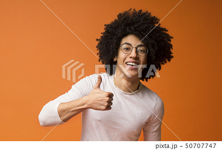 Cheerful african-american curly guy showing thumb up 50707747