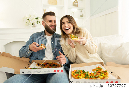 Cheerful Couple Eating Pizza In Front Of TV 50707797