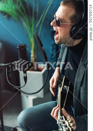 Close up of a man singer sitting on a stool in a 50709714
