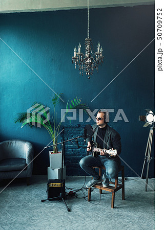 Man singer sitting on a stool in a headphones with Man singer sitting on a stool in a headphones with 50709752