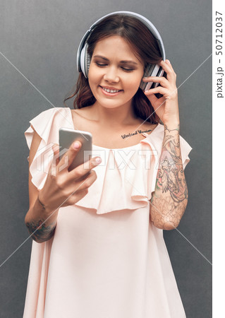 Freestyle. Girl in headphones standing isolated on grey on the city street listening music choosing Freestyle. Girl in headphones standing isolated on grey on the city street listening music choosing 50712037