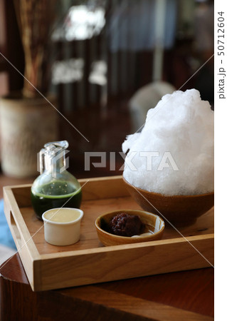 Delicious Japanese sweet shaved ice green tea on wooden table in japanese cafe Delicious Japanese sweet shaved ice green tea on wooden table in japanese cafe 50712604