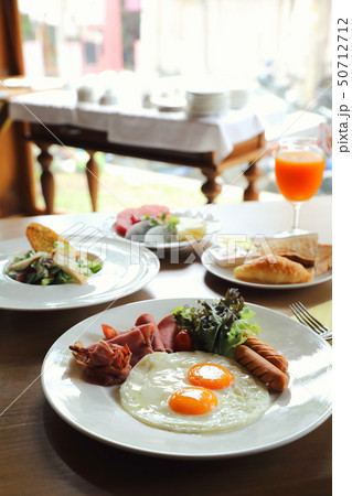 Breakfast set with fried eggs, bacon, sausages, beans, toasts, fresh salad and fruit on wood table Breakfast set with fried eggs, bacon, sausages, beans, toasts, fresh salad and fruit on wood table 50712712