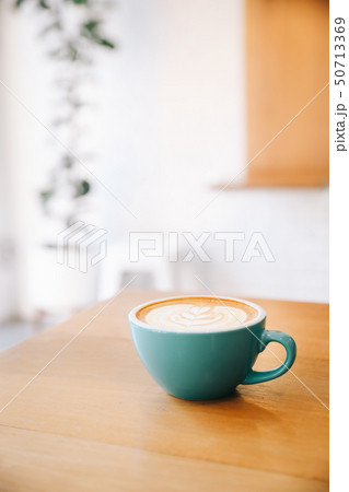 Hot cappuccino coffee in coffee shop on wooden table 50713369