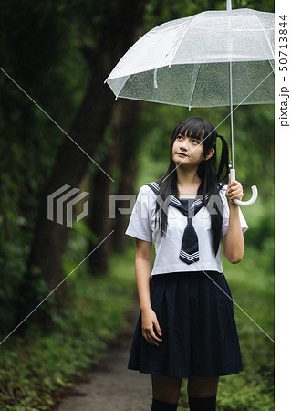 Portrait of Asian school girl walking with umbrella at nature walkway on raining 50713844