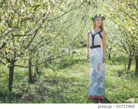 Young beautiful dreaming woman in spring blossom trees. 50717968