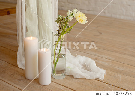 Branch of blooming white peony tulip Mattiola branch in a glass vase white wax candles stand on the 50723258