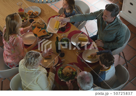 Multi-generation family having food on dining table 50725837
