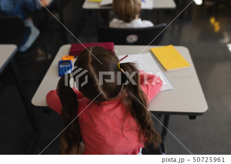 Schoolgirl studying in classroom sitting at desks in school 50725961
