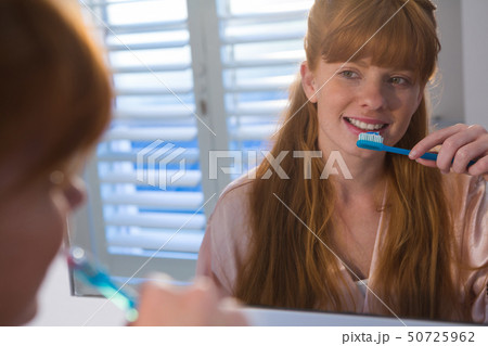 Woman brushing her teeth in bathroom Woman brushing her teeth in bathroom 50725962