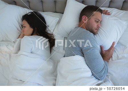 Angry couple avoiding each other in bedroom Angry couple avoiding each other in bedroom 50726054