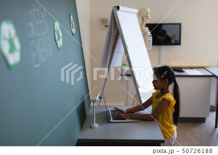Schoolgirl studying on laptop at desk in classroom Schoolgirl studying on laptop at desk in classroom 50726188