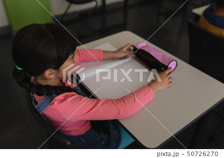 Schoolgirl studying in classroom sitting at desks in school 50726270