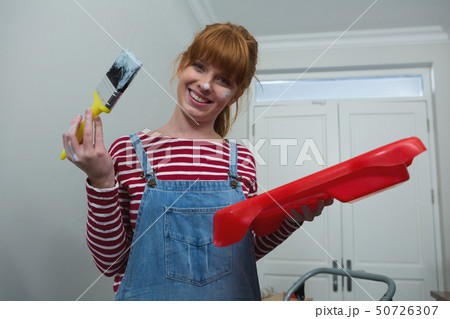 Female painter holding a paintbrush at home Female painter holding a paintbrush at home 50726307