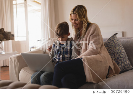 Mother with her son using laptop in living room 50726490