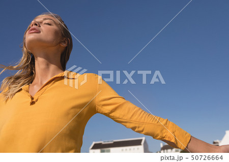 Woman standing with arms outstretched on the beach Woman standing with arms outstretched on the beach 50726664