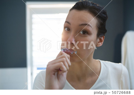 Woman brushing her teeth in bathroom Woman brushing her teeth in bathroom 50726688