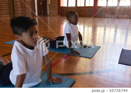 Schoolkids doing yoga on a yoga mat in school Schoolkids doing yoga on a yoga mat in school 50726794