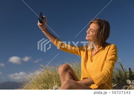 Woman taking selfie with mobile phone at beach Woman taking selfie with mobile phone at beach 50727143