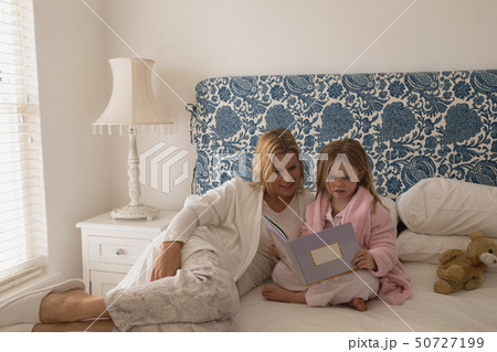 Mother with her daughter reading storybook in bedroom 50727199
